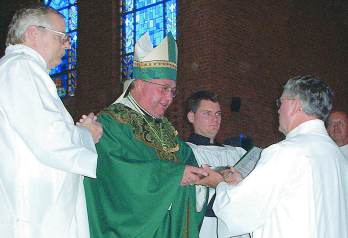 photo of Bishop Morlino presenting deacon candidate with the bread to be consecrated