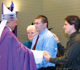 photo of Bishop Morlino greeting catechumen Joseph Knilas and his godparents, Nancy Heflin and Peter Tomlicki