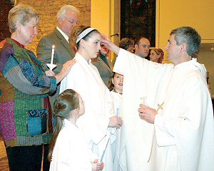 photo of Fr. Randy Budnar, pastor of Holy Rosary Parish, Darlington, confirming a newly baptized member of the Church during the Easter Vigil, March 22