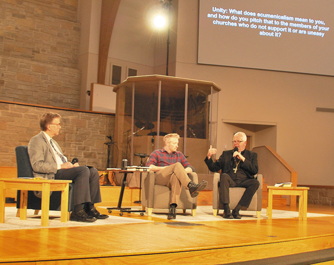 Bishop Donald J. Hying of Madison offers his thoughts on ecumenicism to High Point Church Pastor Nic Gibson, center. During the discussion portion of the presentation, those in attendance could submit questions on their phones to Bishop Hying and Pastor Gibson. Dr. Chris McAtee, left, presented the questions as they were projected onto the wall. (Catholic Herald photo/Angela Curio)