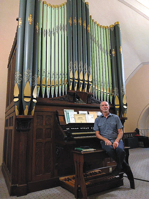 Ken Stancer, organist at St. Martin of Tours Parish in Martinsville, sits by the repainted pipe organ in the church. A recital and rededication of the organ will be held on Tuesday, June 8, at 6:30 p.m.
 (Catholic Herald photo/Molly Schoepp) 